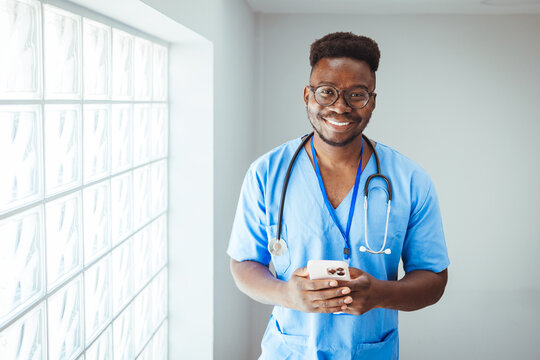 Medical professional working in a hospital. He is dressed in scrubs looking at the camera smiling with a stethoscope around his neck. Happy in his Profession. 