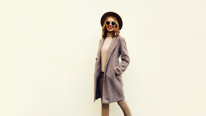 Portrait of beautiful smiling young woman model wearing brown round hat and coat on beige background, blank copy space for advertising text