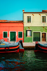 Fototapeta na wymiar Burano dwellings in front of canal with moored boats, vertical