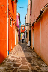 Naklejka na ściany i meble Colorful alley of Burano with tourist walking by
