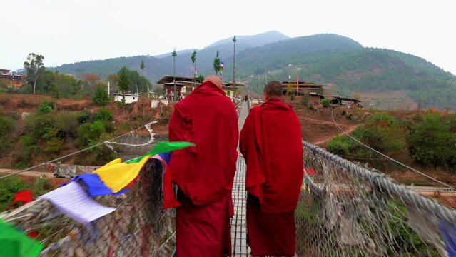 Bhutanese Buddhist monks are walking on the Punakha Suspension Bridge in Bhutan