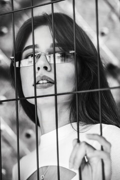 Close-up portrait of woman a in a white blause near a metal grid