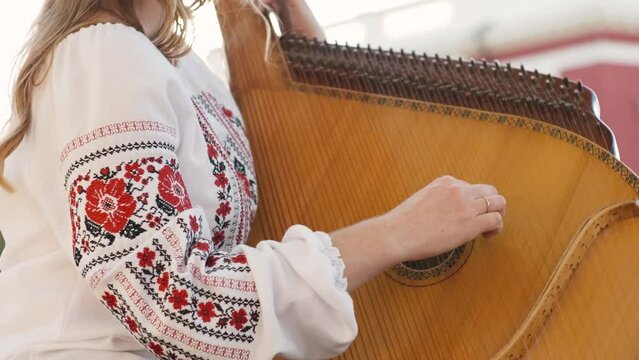 Ukrainian woman folk artist in embroidery shirt playing the bandura