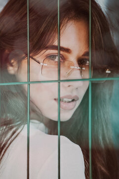 Close-up portrait of woman a in a white blause near a metal grid