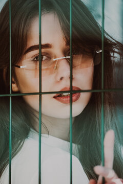 Close-up portrait of woman a in a white blause near a metal grid