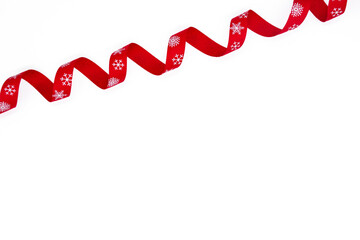 Fototapeta na wymiar A red curling bright ribbon with snowflakes on a white background. Copy space. The concept of Christmas, St Valentine Day and gifts