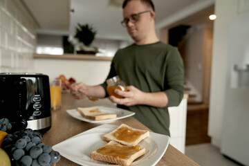 Fototapeta na wymiar Adult caucasian man with down syndrome preparing breakfast