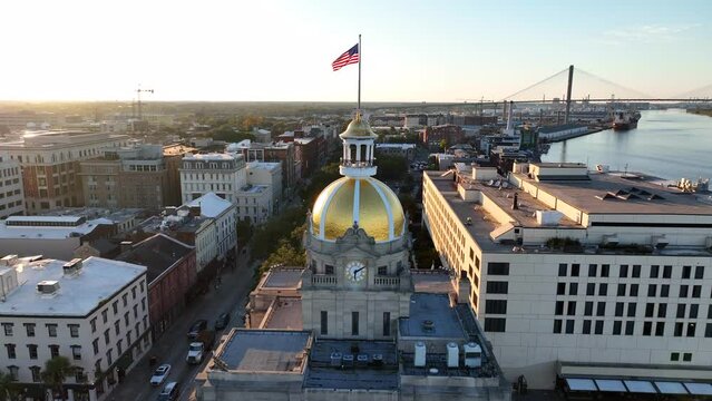 Savannah Georgia aerial establishing shot at night. American flag with Savannah River and downtown historic district. Golden hour sunset.
