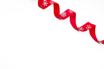 A red curling bright ribbon with snowflakes on a white background. Copy space. The concept of Christmas, St Valentine Day and gifts
