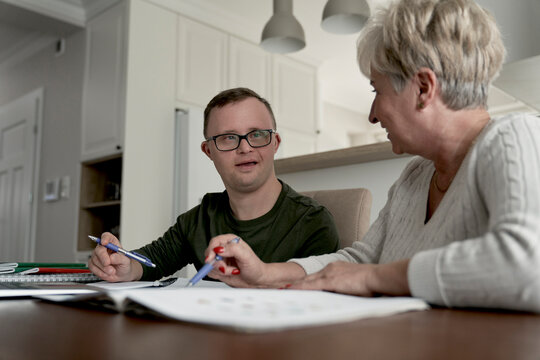 Caucasian man with down syndrome learning with his mum at home