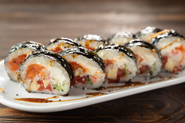 Fototapeta Maki sushi over white plate. appetizing sushi roll futomaki with cucumber and salmon. Japanese cuisine. obraz
