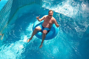 Overweight european tourist in aerial lap water park swims in the pool.