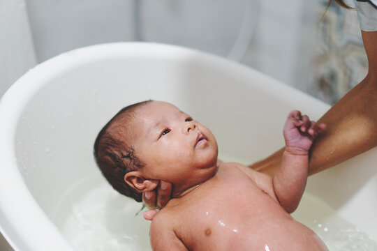hands of mother holding small toddler girls in a bathroom indoors at home. mom, kid and healthcare concept