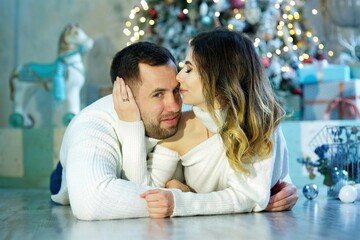 A young couple in a room decorated for Christmas or New Year.