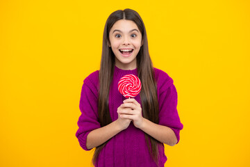 Funny child with lollipop over yellow isolated background. Sweet childhood life. Teen girl with yummy caramel lollipop, candy shop. Teenager with sweet sucker.