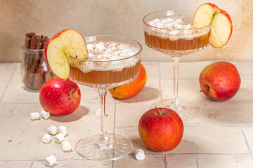 Apple cider marshmallow cocktail, tasty apple juice martini with autumn spices and marshmallows, with fresh apple on beige background