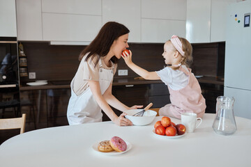 An image of a young woman and her little cute daughter are cooking in the kitchen. Have fun...