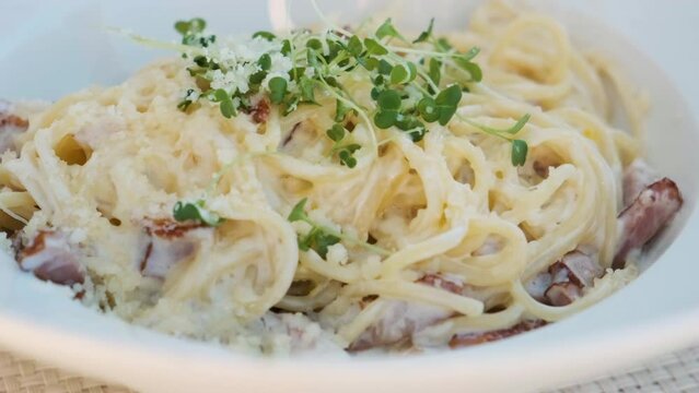 Close up of pasta spaghetti carbonara in a plate in summer cafe. Italian food. Close up. 4k video