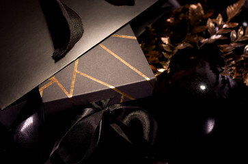 Black Friday Shopping Concept with Black color gift box decorated with Gold Stripes laying on Black baloons.