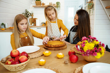 Mom and daughters decorate pumpkin pie for Thanksgiving holiday