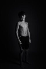 Fototapeta na wymiar Happy boy posing with bathing suit, black and white studio photography