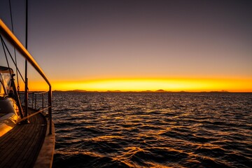 sunset over the ocean in golden light with waves and yachts