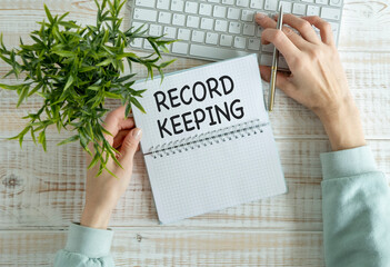 RECORD KEEPING text written on a notebook on the wooden background