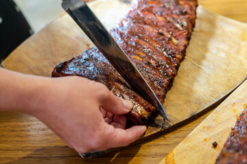 Cooker's hand cut tasty smoked pork ribs on wooden desk