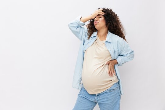 Pregnant woman fatigue back pain and headache on white isolated background in t-shirt with blue shirt