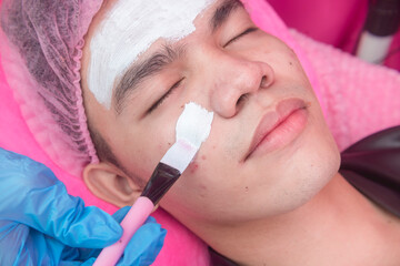 An Esthetician applies post treatment collagen cream with a brush. Procedure after a diamond peel at an Aesthetic center or dermatology clinic.