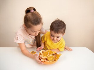 Children eat delicious and healthy dried fruit. The concept of healthy food. Oranges and apples in...