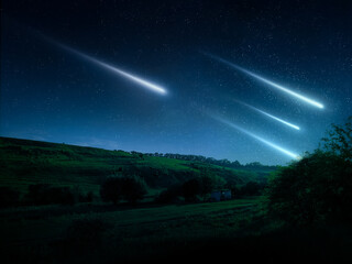 Night landscape with meteors in the starry sky. Beautiful shooting stars over green hills and...