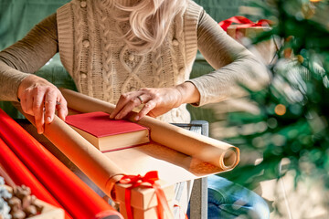 Wrapping christmas gifts. Blond woman wrapping presents in recycled card and decorated it with...