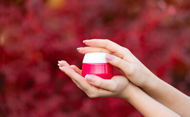 hands holding and applying nourishing cream jar for skincare