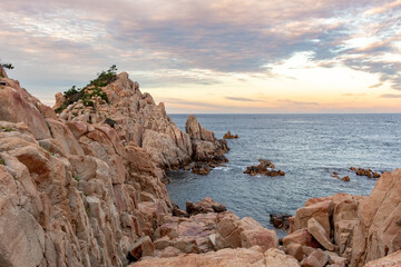 Red rocky coastline overlooking the ocean at Daewangam Park in Ulsan South Korea during a colorful golden sunset