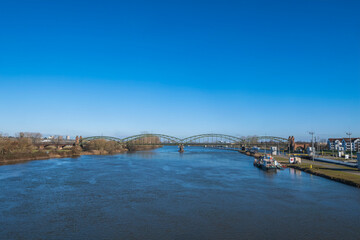 View from the barrage of the Main near Kostheim - Germany on the river with the old railway bridge in the background under a bright blue sky