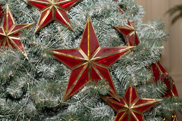 Red christmas toy in the shape of a star on the new year and christmas tree. Close up