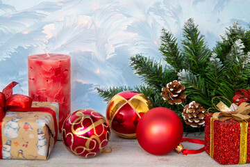 Christmas mood, New Year background. Christmas tree branches, red Christmas balls, a candle and gift boxes on a background of frost patterns. Holiday atmosphere.