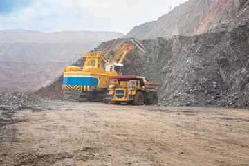 The process of loading rock mass with an excavator into a heavy-duty vehicle in a quarry....