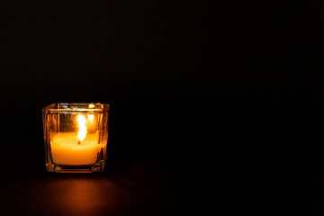 Candle in a glass beaker on a black background