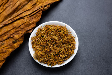 Tobacco leaves and cut tobacco on black background