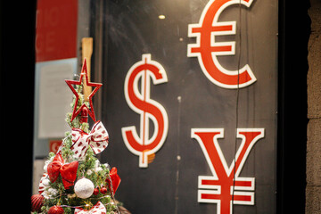 Stylish christmas tree with ornaments and currency exchange signs in store showcase in evening....