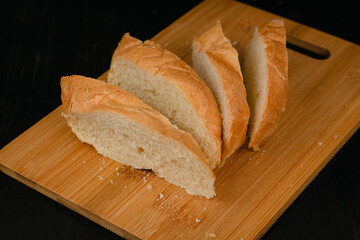 Sliced white bread lies on a cutting board on a wooden background