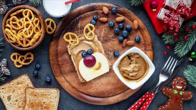 Making cute smiling Christmas reindeer sandwith with peanut butter and fresh fruit for kids. Stop motion animation