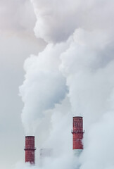 Smoke and steam rise from industrial chimneys of a heating power plant.