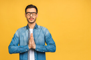 Fototapeta premium Concentrated relaxed person, standing with closed eyes, having relaxation while meditating, trying to find balance and harmony. Yoga and meditation concept. Isolated over yellow background.