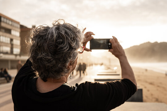 Elderly woman taking photo of beach