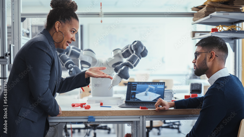 Poster Black Senior Engineer Talks to Young Male Computer Scientist while Analysing Robotic Arm in the Research Laboratory. Specialists use Laptop, Find Solution. Innovative Startup Company.