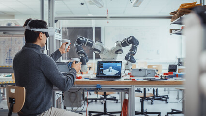 Male Engineering Student Wearing AR Headset, Designs and Manipulates Robot Hand by Using Controllers. Futuristic Virtual Reality Design and Mixed Technology Professional Application Concept.