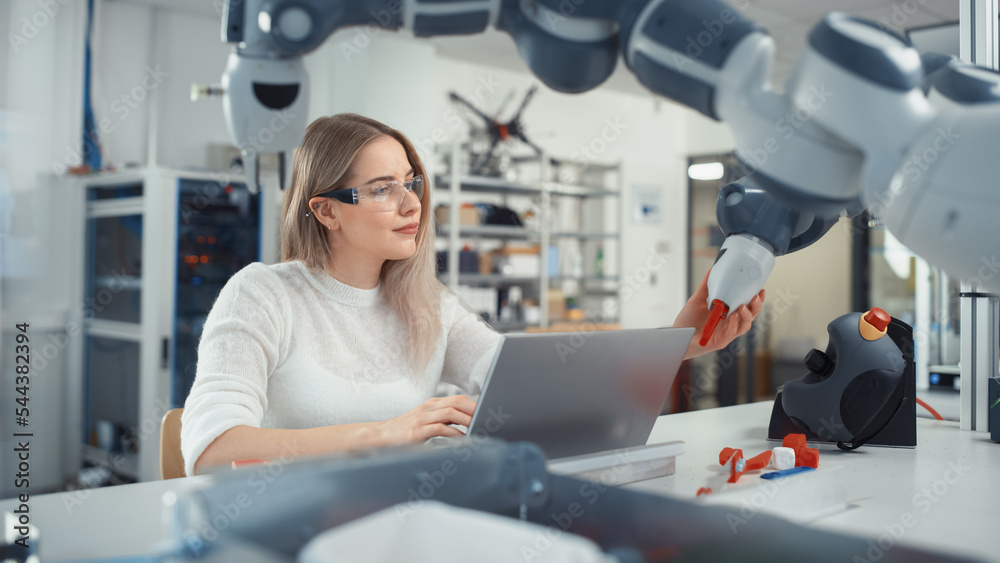 Poster Female Automation Engineer Writes Code on Laptop and Moves Bionic Claw At the Factory. Modern and Futuristic Robotic Equipment Starts the New Era in Computer Science, Machine Learning.
